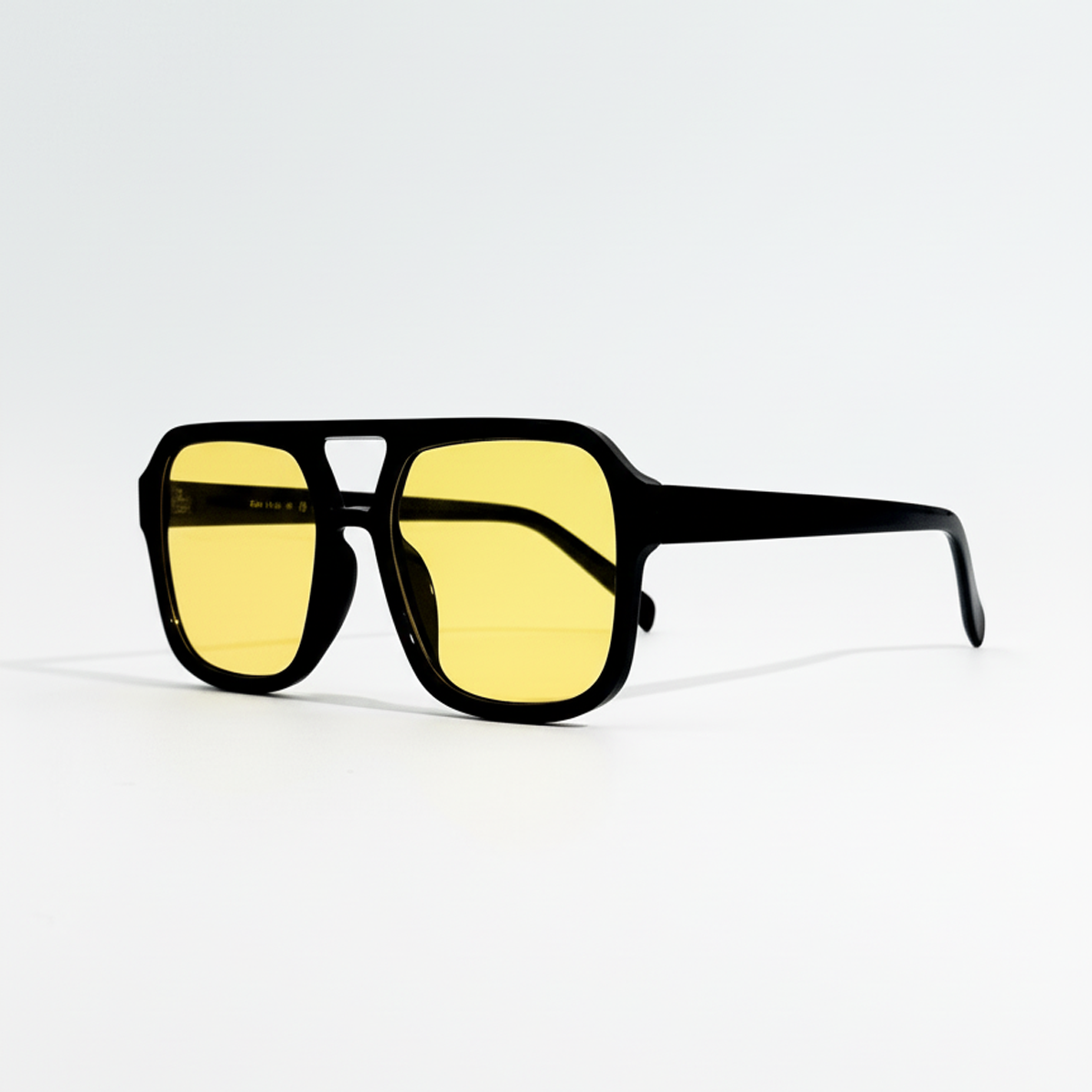 Amber pilot sunglasses with black polycarbonate frame and yellow lenses, shown at an angle.