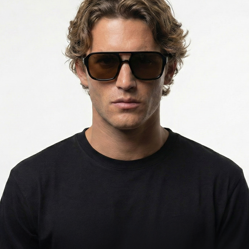 Man wearing amber pilot sunglasses with black frames and brown lenses.
