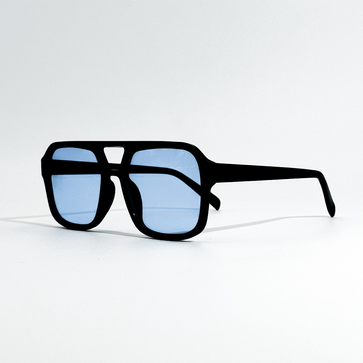Arctic Noir black frame sunglasses with light blue lenses, SS26 Retro Collection.