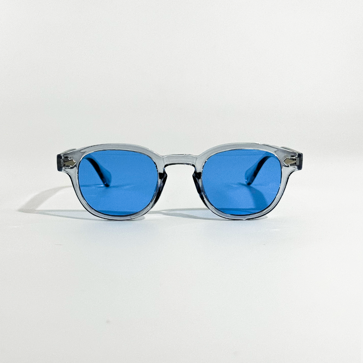 Blue Mirage SS26 Circle Collection sunglasses with clear gray frames and vibrant blue lenses.