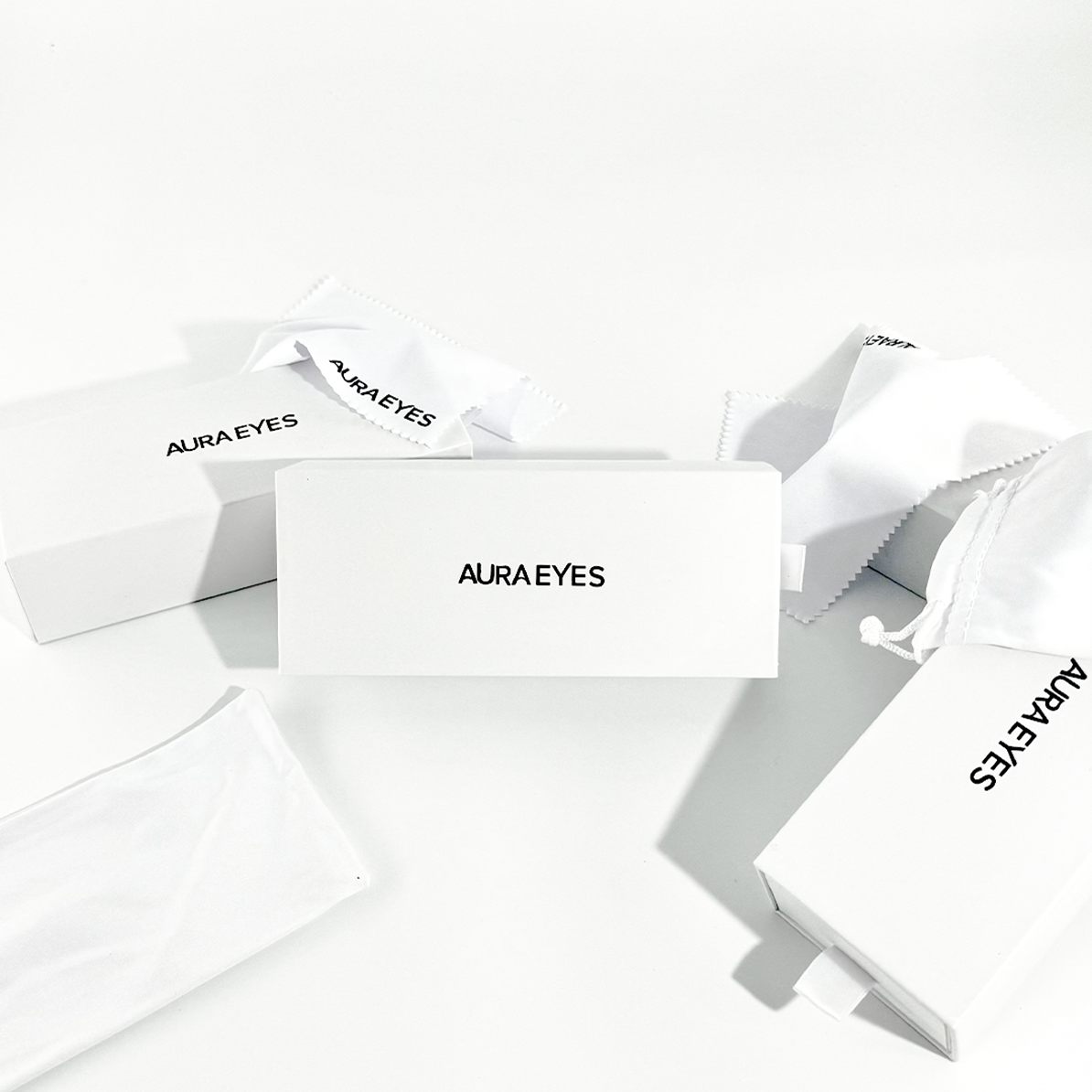 Aura Eyes white packaging boxes, soft pouches, and cleaning cloths on a white background.