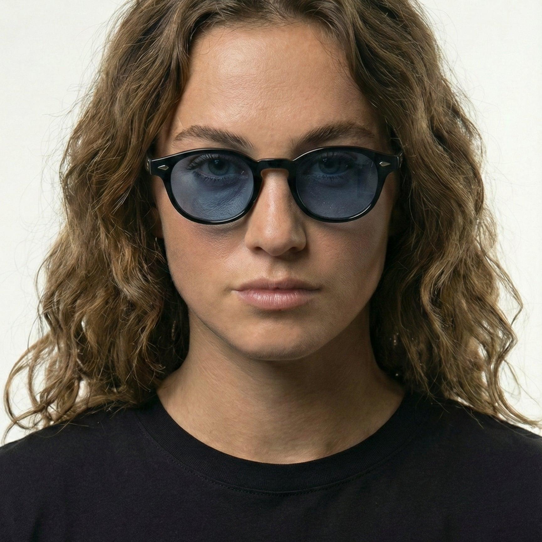 Woman wearing black SS26 Circle Collection sunglasses with mystical sky blue lenses.